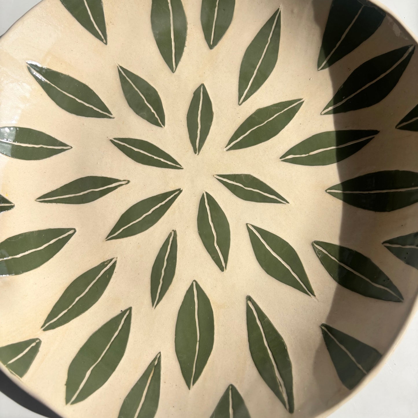 Ceramic plate with green leaf pattern on a white background