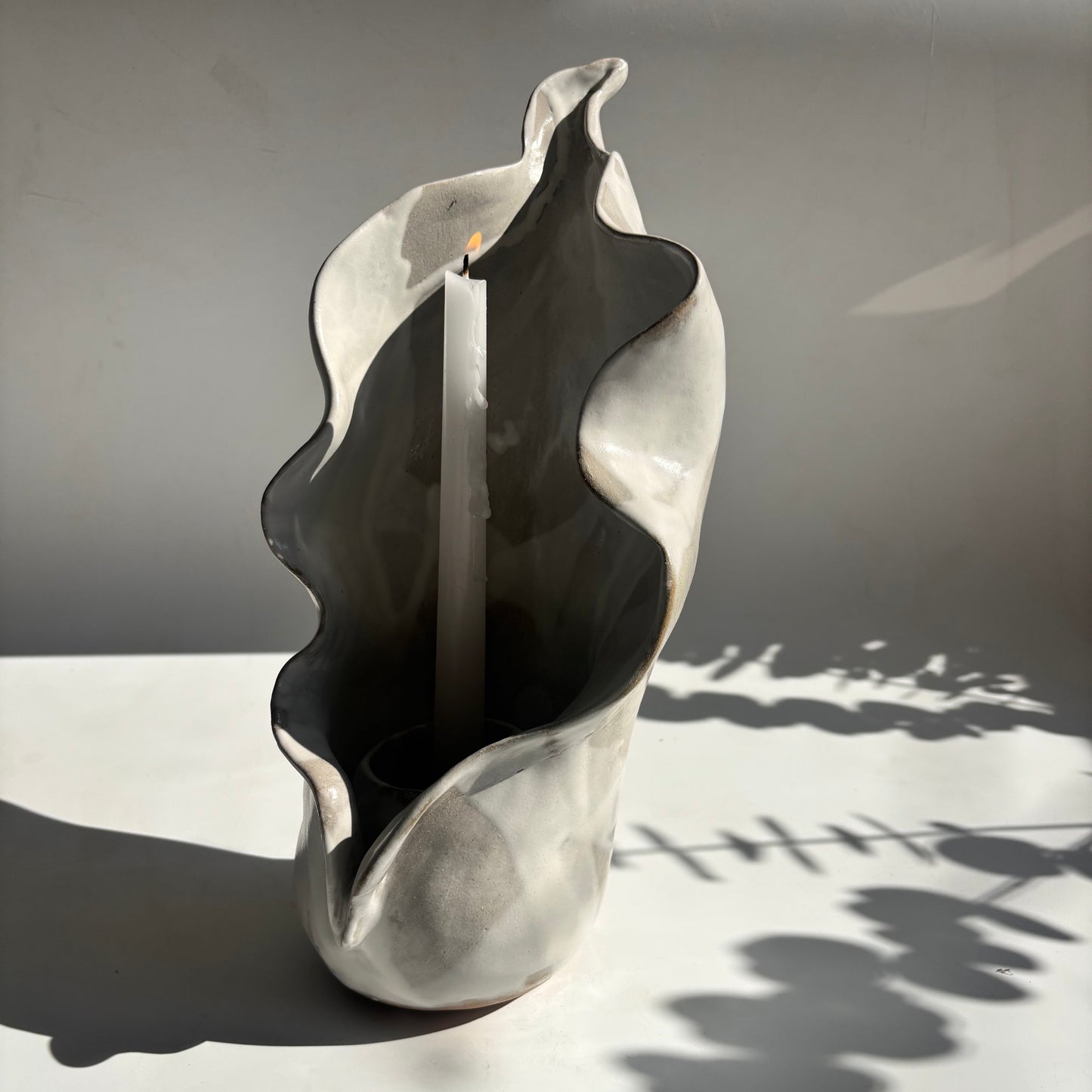 Decorative metal sculpture of a calla lily against a gray wall.