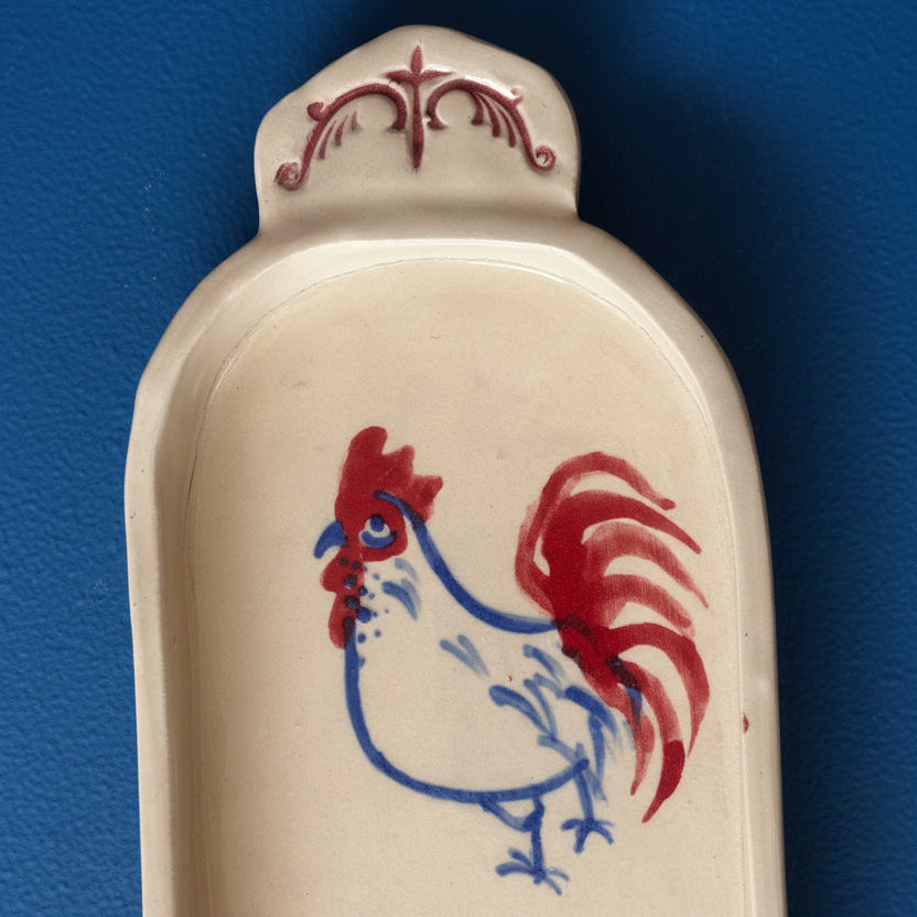 Ceramic tray with a red and blue rooster design on a white background