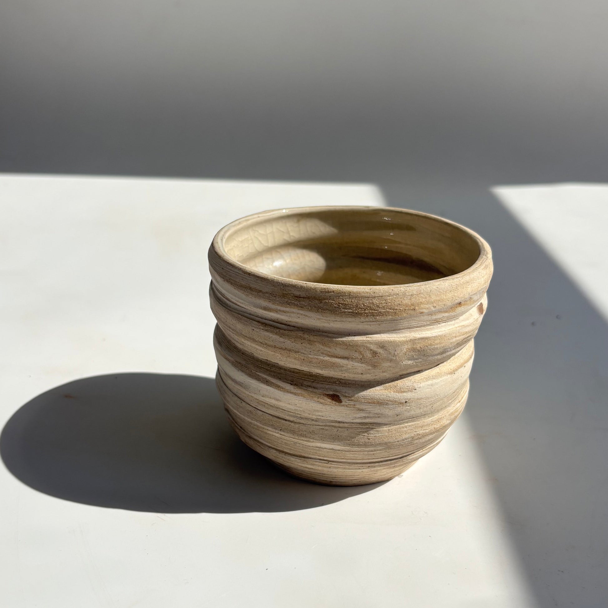 Wooden vase against a white wall with soft shadows