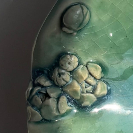 Close-up of a ceramic piece with textured surface and embedded stones.