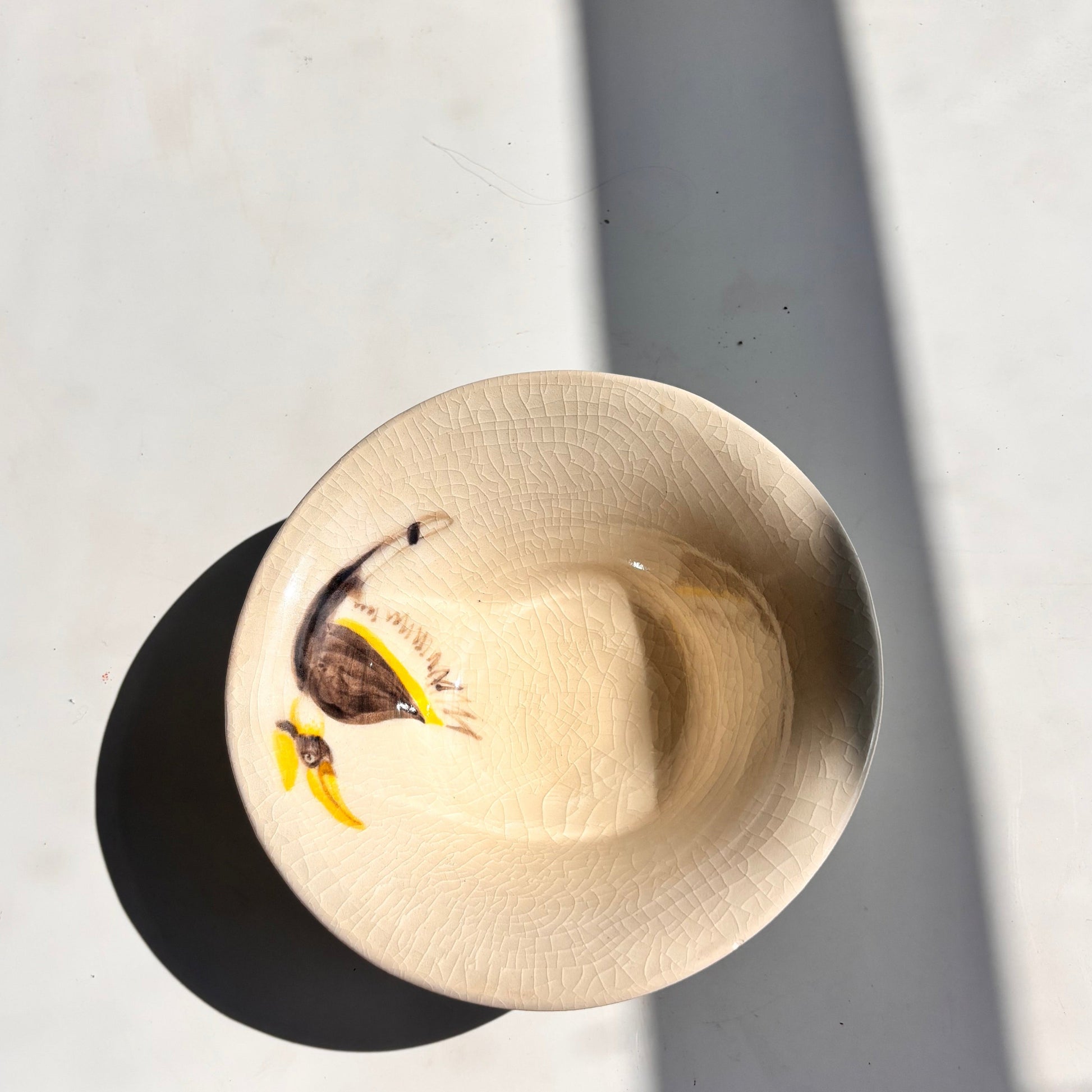 Gold-colored bowl with a small object inside on a light gray surface