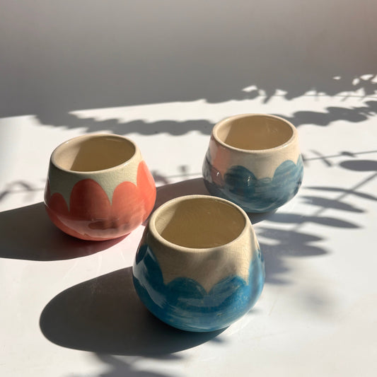 Three ceramic cups with marbled designs on a white wall.