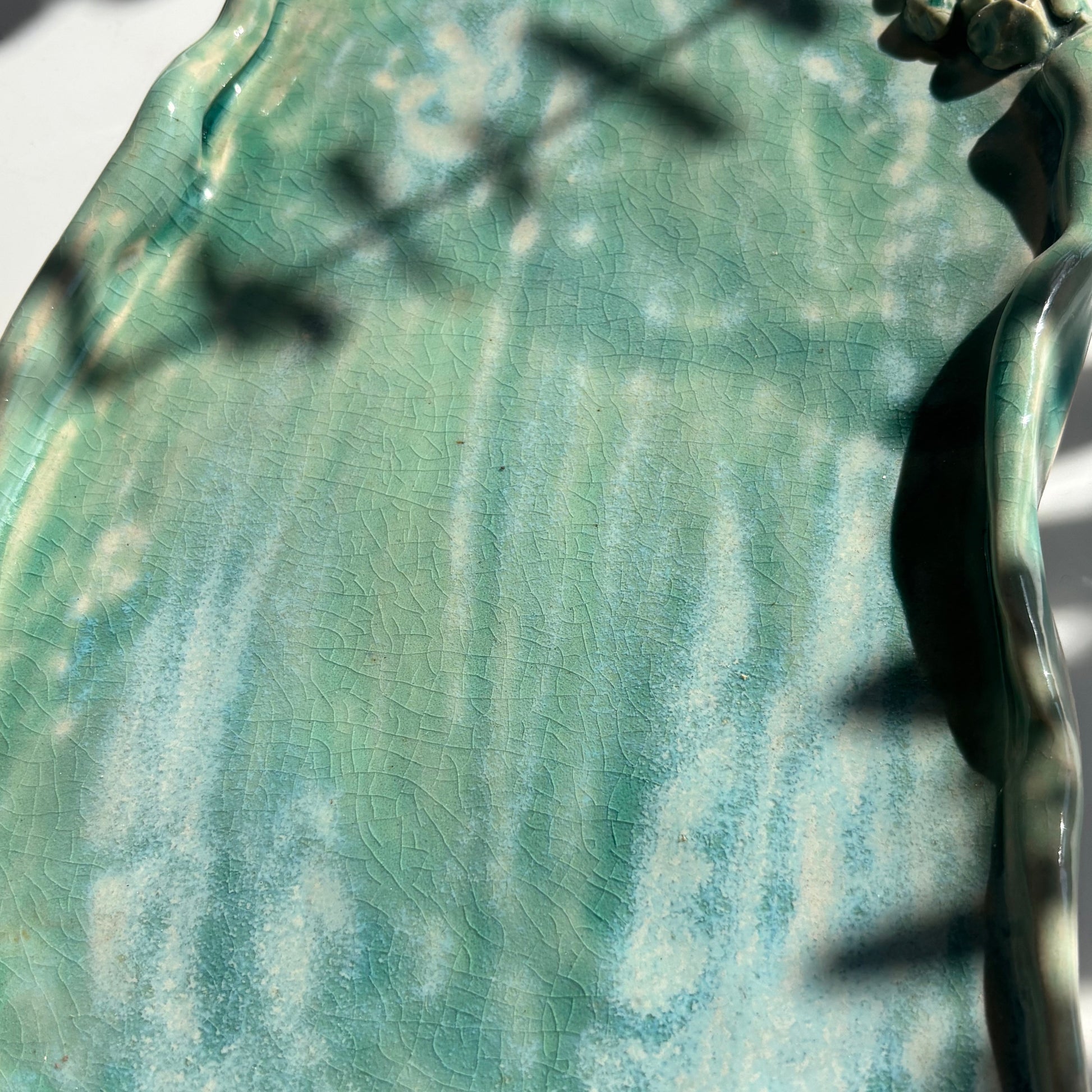 Close-up of a textured green ceramic plate with a decorative edge.