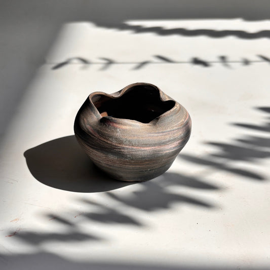 Ceramic bowl on a light surface with shadows from leaves