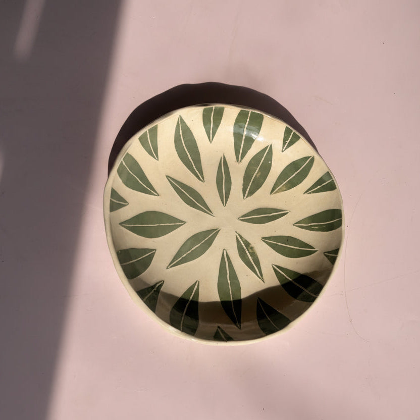 Round decorative object with leaf pattern on a plain background