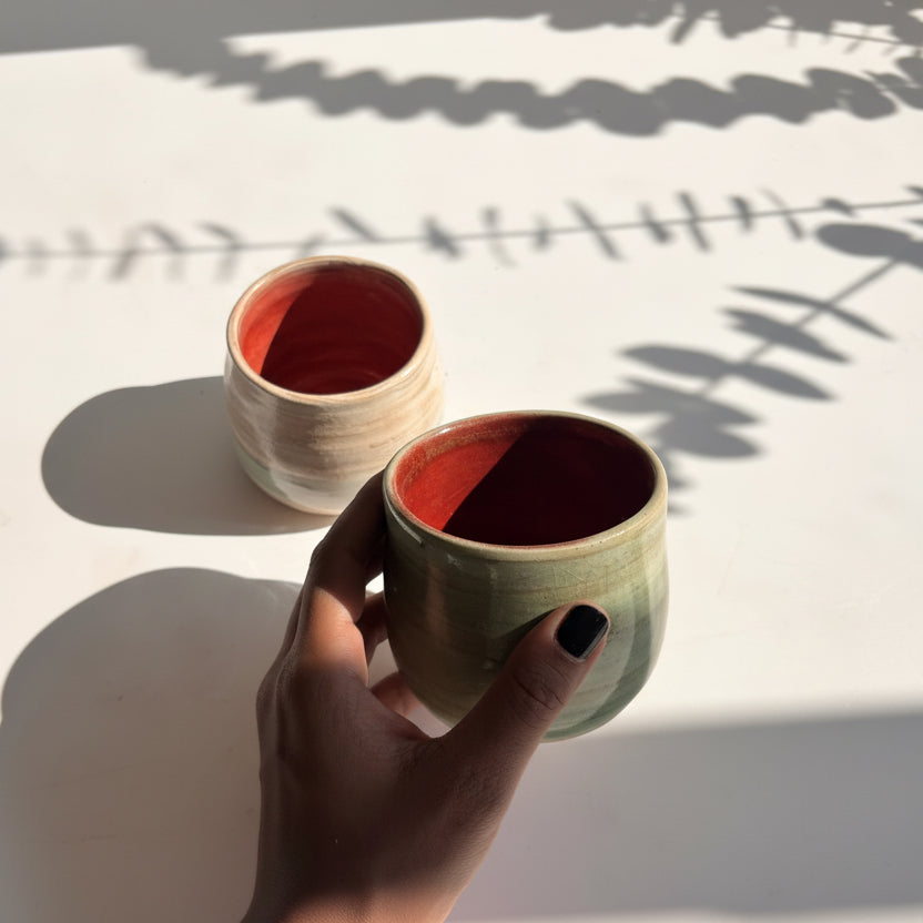 Hand holding a cylindrical ceramic object against a white background