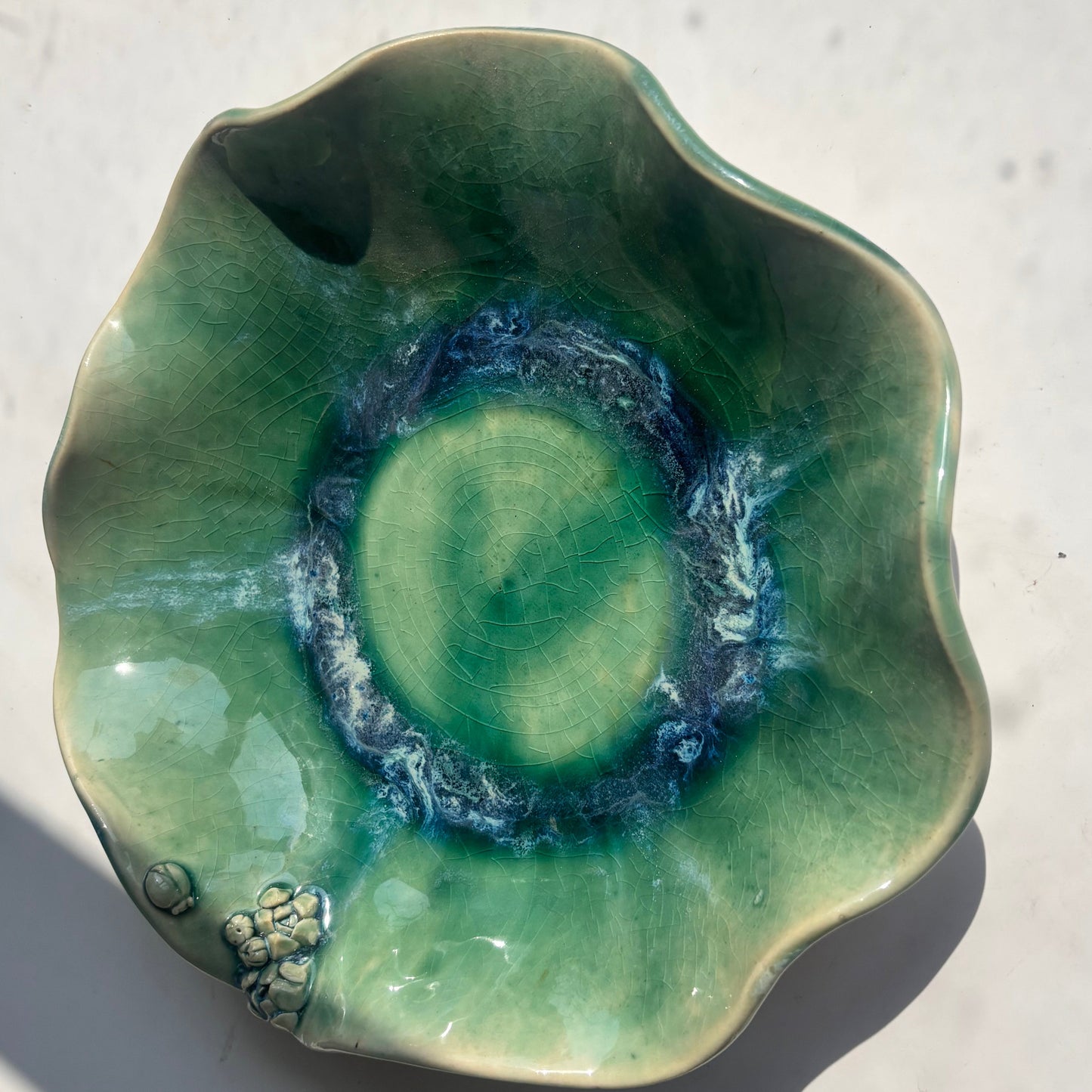 Green ceramic dish with swirling pattern on a light surface
