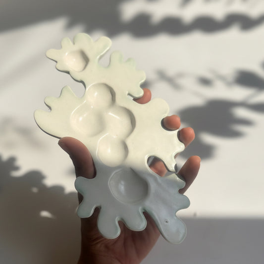 Hand holding a white snowflake-shaped ice cube tray on a light background