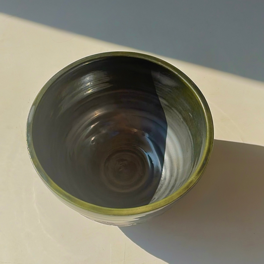 Ceramic bowl with green rim on a white surface