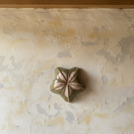 Decorative ceramic wall piece on a textured wall with wooden beams above
